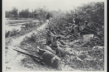 U.S. soldiers lie behind an embankment, watching the enemy, 1899