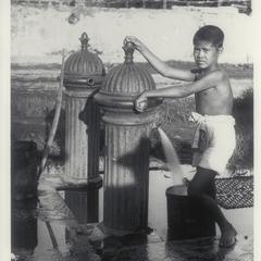 Boy getting water from public fountain, early 1900s