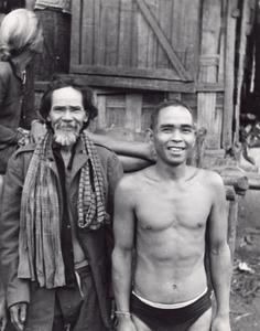 Two Nyaheun men stand in front of a house in a Nyaheun village in Attapu Province