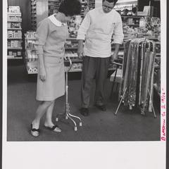 A pharmacist helps a customer select a cane