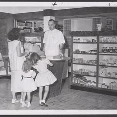 A pharmacist assists a shopper and her young daughters