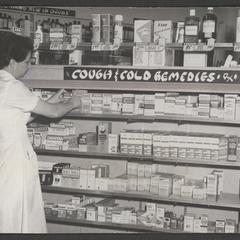 Woman stocks cough and cold remedies shelves in drugstore