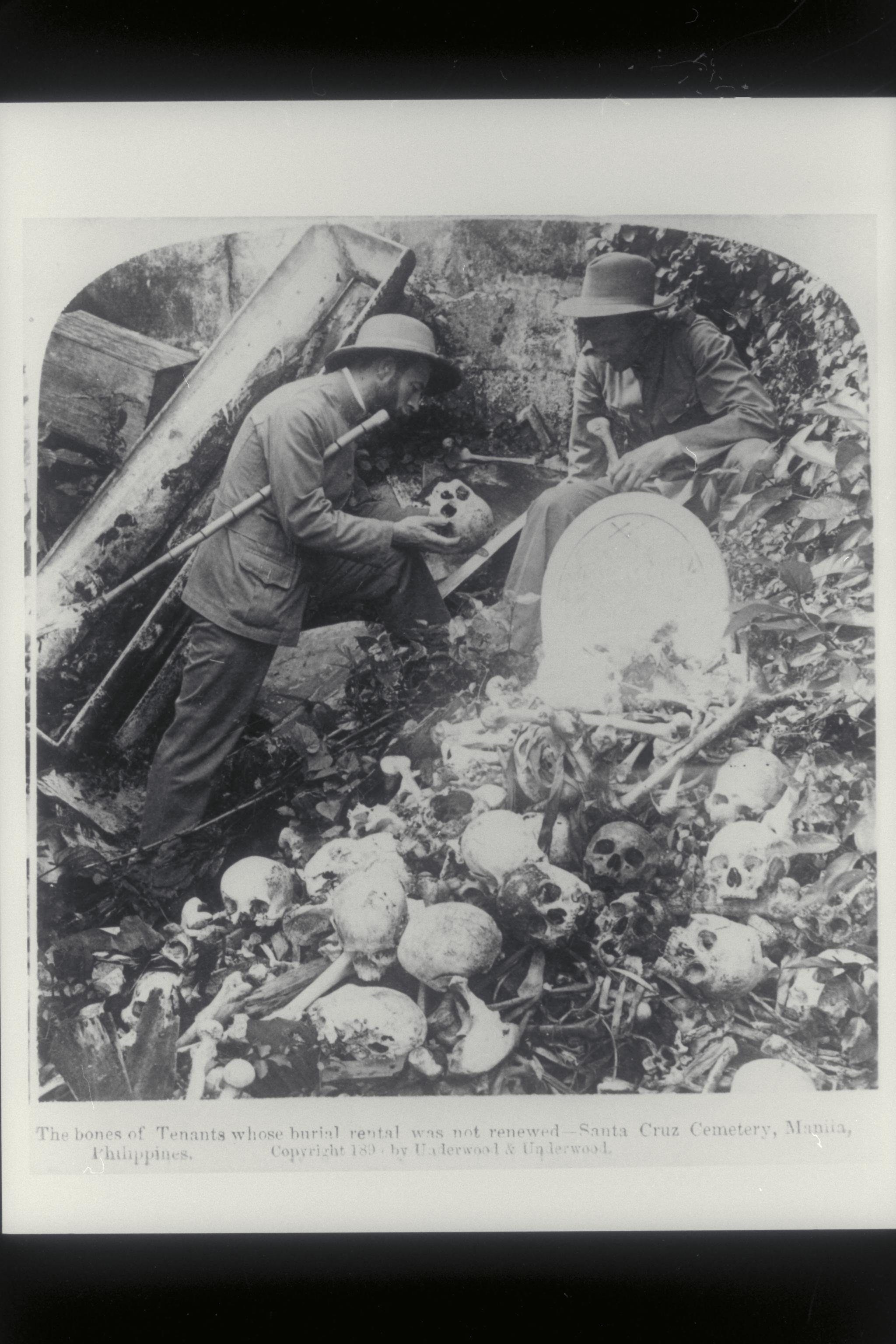 Two men examine a skull in the bone pit at Santa Cruz Cemetery