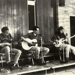 Three men singing and playing guitar