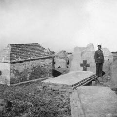 An unidentifiable military figure standing in a Christian graveyard.