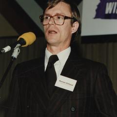 Norman Gilliland at standing microphone with nametag