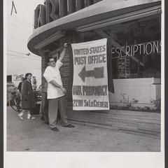 Man holds a sign for a new post office substation in a drugstore