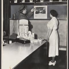 A pharmacy clerk talks to a customer about the store's apothecary jars