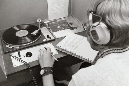 Student listening to a record a taking notes