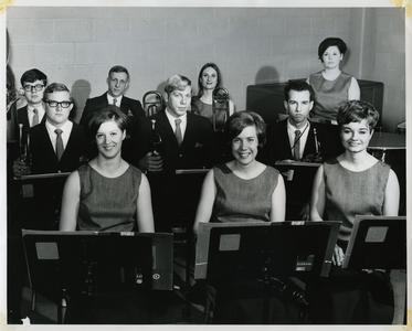 Stout Symphonic Singers and Wind Ensemble members, sitting in front of music stand holding instruments