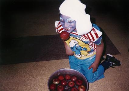 Boy in costume bobbing for apples