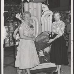 A saleswoman helps a customer select items in a drugstore vacation display
