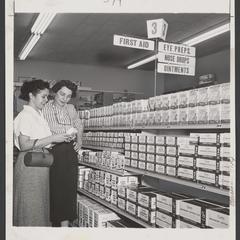 Two women read a package in a drugstore first aid aisle
