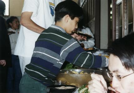 Boy getting food at 1999 Multicultural Graduation Reception