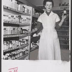 A pharmacy salesclerk points to pricing on shelves