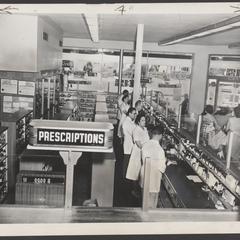 Pharmacists line up at work behind the prescription counter