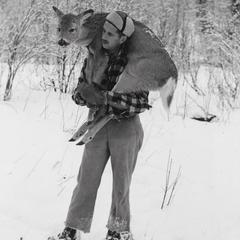 Bill Feeney carrying deer on shoulders