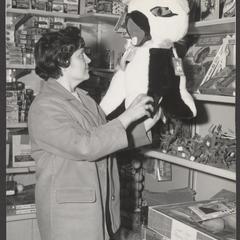 A woman holds a large stuffed animal in a toy section