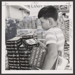 A young boy selects school supplies from a drugstore display