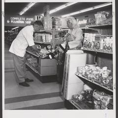 A salesman assists a woman with a young child in the toy department