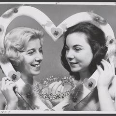 Two women pose in a heart frame