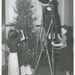 Young Women's Christian Association members decorating Christmas trees in front of the Harvey Memorial