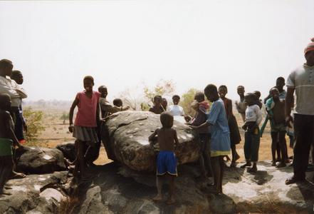Children gathered around a large rock