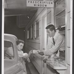 Pharmacist hands a woman her prescription through the drive-in window