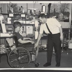 A pharmacist talks to a customer about the features of a wheelchair