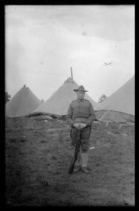 Soldier in front of camp tents
