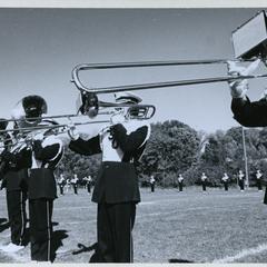 Stout marching band performing on the football field, trombone section up close