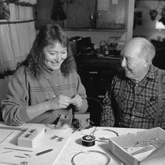 Vicki Doxtator works on silver jewelry as Edwin Martin watches