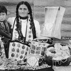 Ojibwa woman and child pose with beadwork and mats