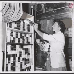 A salesclerk loads a stock elevator with boxes of Kleenex brand tissue