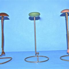 Three metal hat stands with painted tops