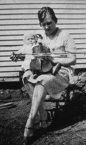 Baby holds violin on woman's lap