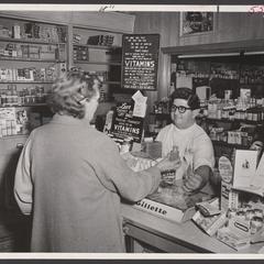 A pharmacist advises a shopper on a vitamin brand