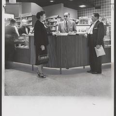 A pharmacist helps two customers