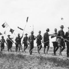 A group of marching soldiers carrying flags.
