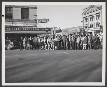 Group of people poses in the street in front of a drugstore