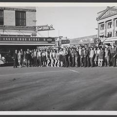 Group of people poses in the street in front of a drugstore