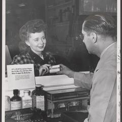 A pharmacist helps a customer at a drugstore counter
