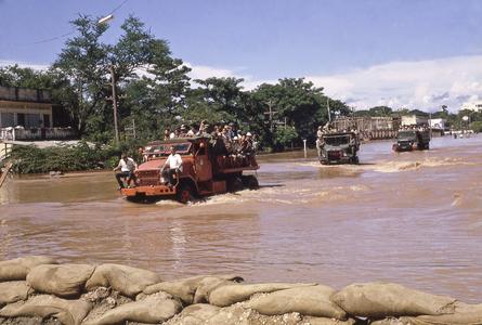 Military trucks navigate through the flood