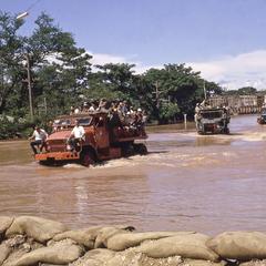 Military trucks navigate through the flood