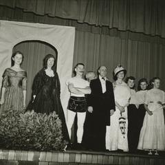 Several women and men dressed in various costumes standing on a stage.