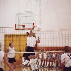 Volleyball player spikes ball over net