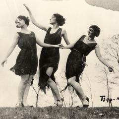 Three women dancing by lake.