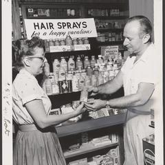 Two people view a display of hairspray products in a drugstore