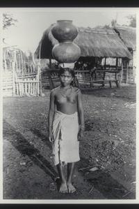 Young woman carrying pottery on her head, Mountain Province, ca. 1920-1930