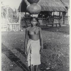Young woman carrying pottery on her head, Mountain Province, ca. 1920-1930